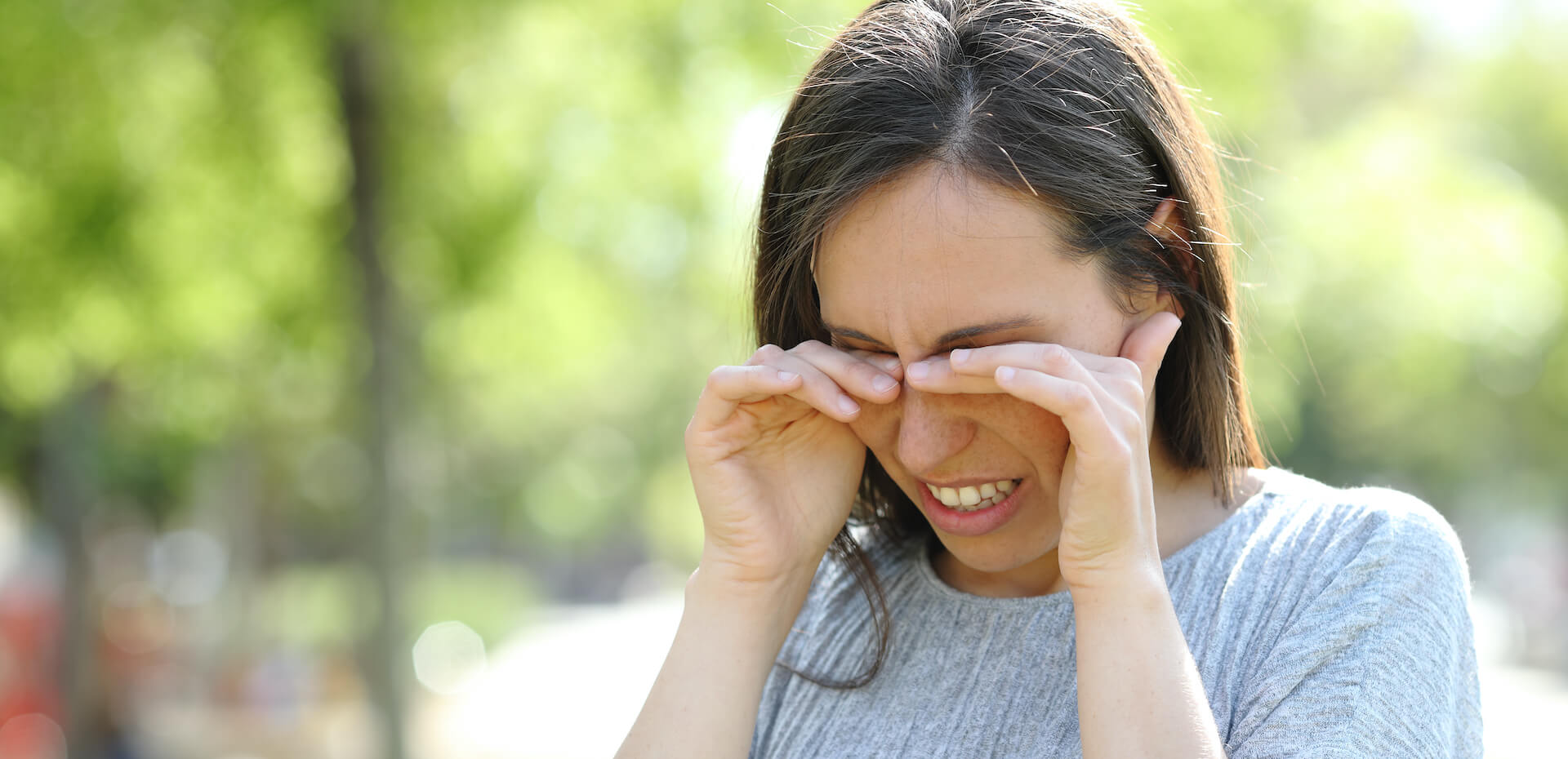 woman rubbing eyes outside